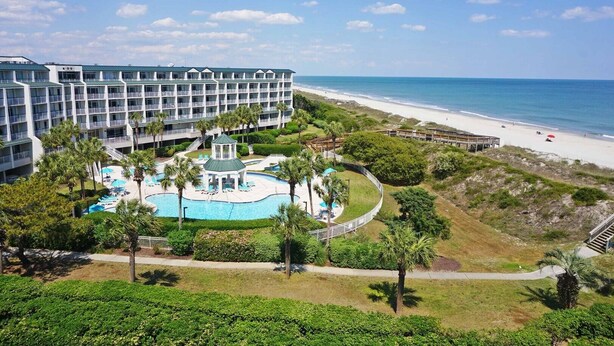A hotel with a pool, beach access, and a view of the ocean.