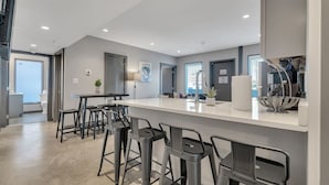 Una cocina moderna con barra, taburetes y un ventanal grande.