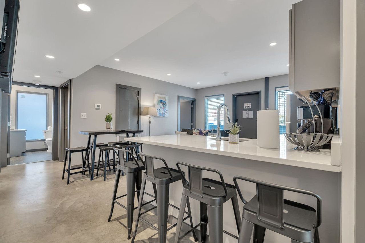 A modern kitchen with a bar area, bar stools, and a large window.