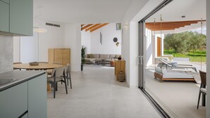 A modern interior with a dining area, sofa, and a view of the outdoors.