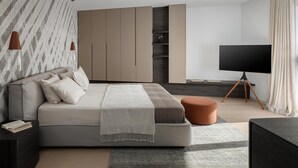 A modern bedroom with a large bed, a TV on a stand, and built-in storage.