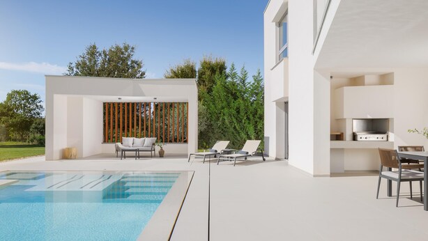 A modern outdoor pool area with lounge chairs, a dining table, and a built-in kitchen area.