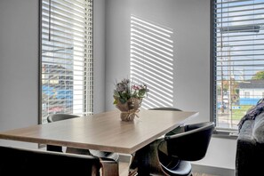 Une salle de conférence avec une table en bois, des chaises noires et un vase de fleurs.