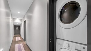 Une buanderie équipée d’un lave-linge et d’un sèche-linge, avec un plancher en bois et un couloir menant à une porte.