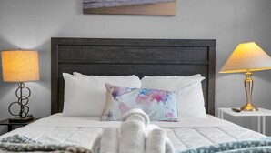 Un lit bien fait, avec des draps blancs, un coussin décoratif et une serviette pliée posée sur le lit.