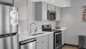Une cuisine moderne dotée d’appareils électroménagers en acier inoxydable, de meubles de rangement gris et d’un plan de travail blanc.