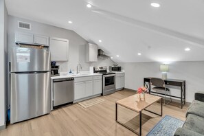 Une cuisine moderne avec des meubles blancs, des appareils en acier inoxydable et un coin repas comprenant une table et des chaises.