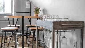 A kitchen with a wooden table and bar stools, a wine rack with glasses, and a refrigerator. - Cozy New Build - 5min to FQ/Frenchman+Parking (New Orleans)
