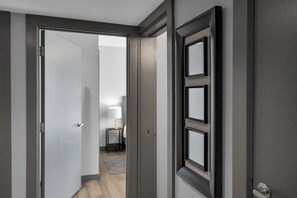 Un pasillo con una puerta que da a una habitación con una lámpara y una mesita.