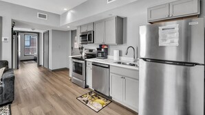 A modern kitchen with stainless steel appliances, grey cabinets, and a built-in microwave. - Cozy New Build Near FQ/Frenchman+Parking (New Orleans)
