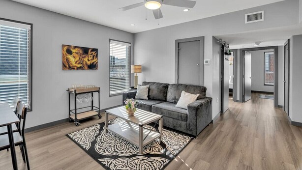 A modern living room with a grey sofa, a coffee table, and a ceiling fan. - Cozy New Build Near FQ/Frenchman+Parking (New Orleans)