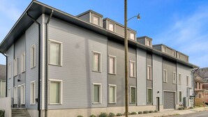 A modern two-story residential building with a flat roof, large windows, and a visible front entrance.