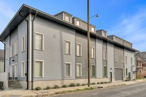 Un immeuble résidentiel moderne à deux étages, doté d’un toit plat, de grandes fenêtres et d’une entrée bien visible à l’avant.