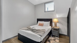 A bedroom with a bed, a nightstand, a lamp, a ceiling fan, and a window. - Bywater Haven: Near FQ&Frenchman + Secure Parking (New Orleans)