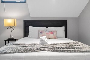 Un lit bien fait, orné d’un coussin représentant une carte du monde, une lampe de chevet et une serviette posée sur le lit.