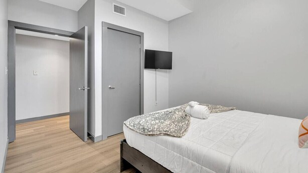 A bedroom with a bed, a wardrobe, a television, and a door.