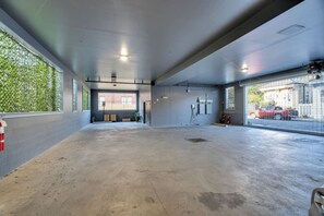 A spacious indoor area with a concrete floor, large windows on one side, and a view of a red vehicle outside.