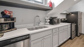 A modern kitchen with a dishwasher, sink, and stainless steel appliances.