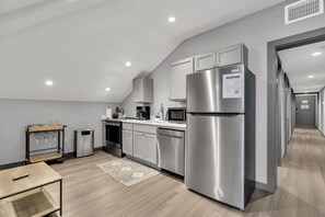 Eine moderne Küche mit Edelstahlgeräten, weißen Schränken und Holzboden.