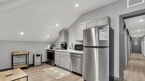 A modern kitchen with stainless steel appliances, white cabinets, and a wooden floor.
