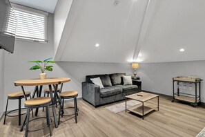 Ein Loft-Wohnzimmer mit einer Couch, einem Couchtisch und Barhocker.