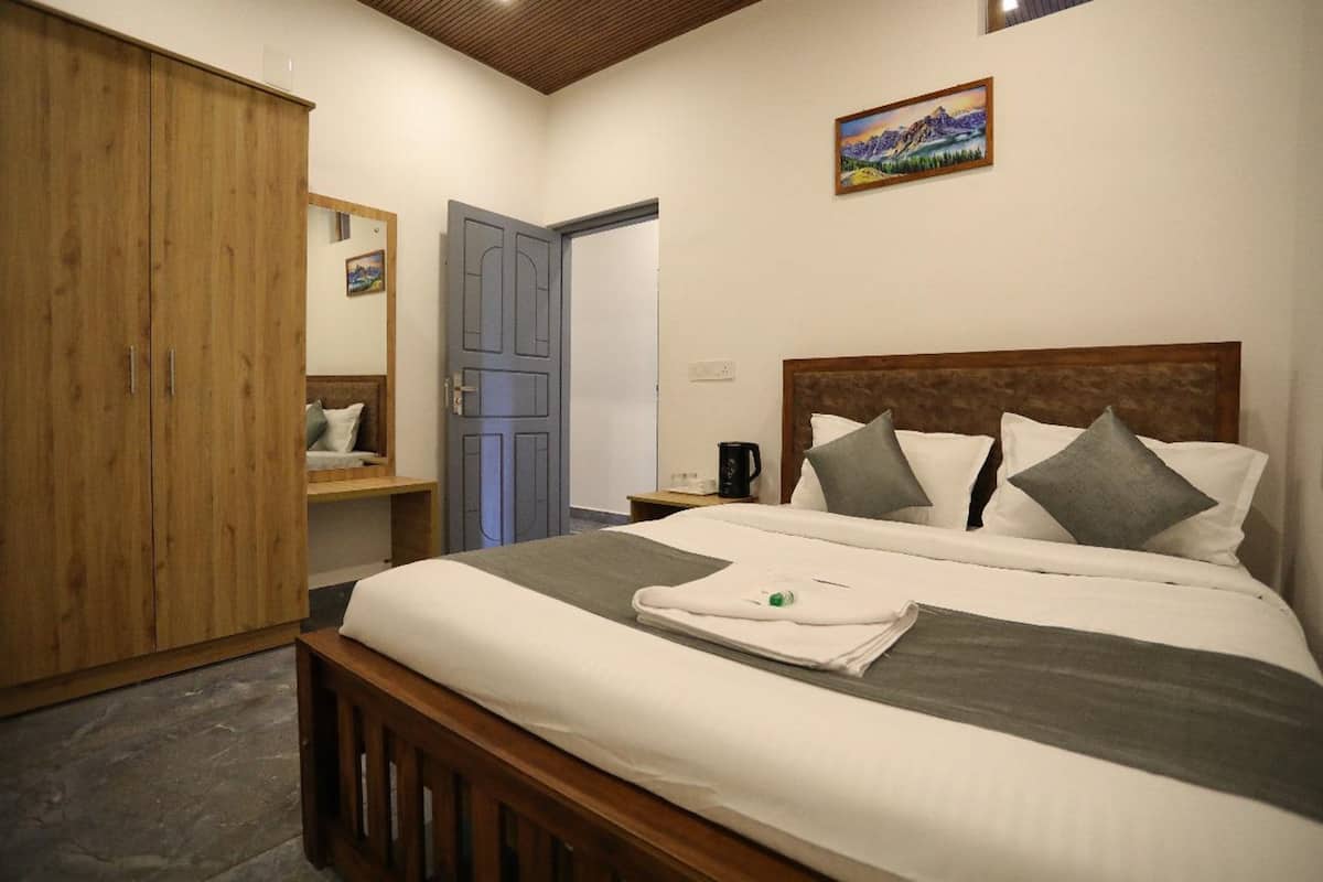 A bedroom with a wooden bed, a wardrobe, a bedside table with a coffee maker, and a painting on the wall.