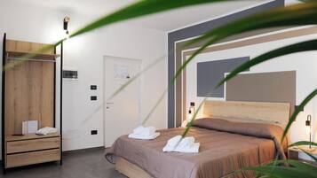 A hotel room with a bed, a wooden wardrobe, a door, and a nightstand with a lamp.