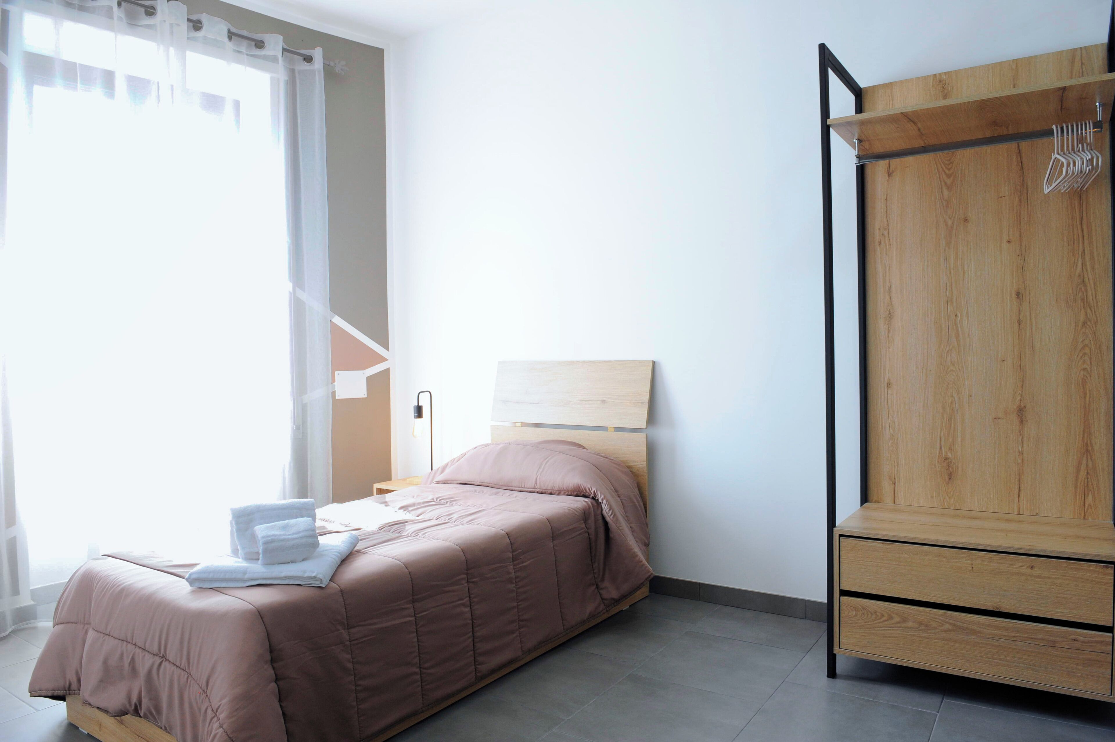 Une chambre à coucher avec un lit, une armoire en bois et une table de chevet.