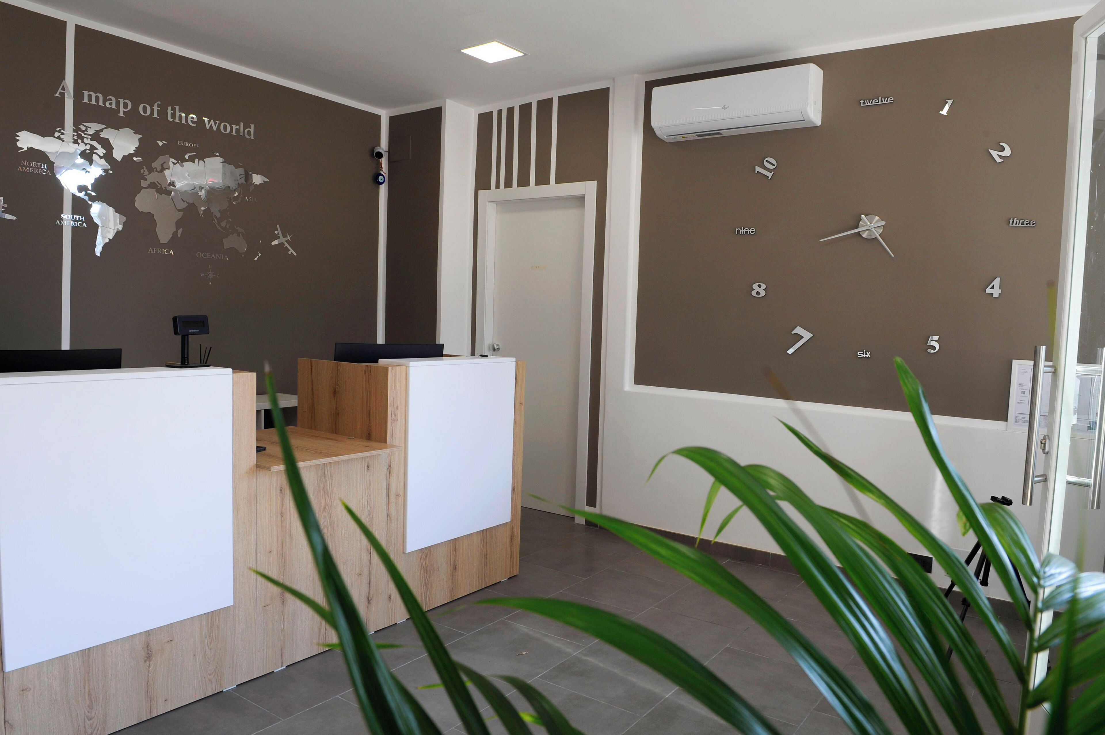 Zona de recepción con un mapa mundial en la pared, un reloj y mostrador de recepción.