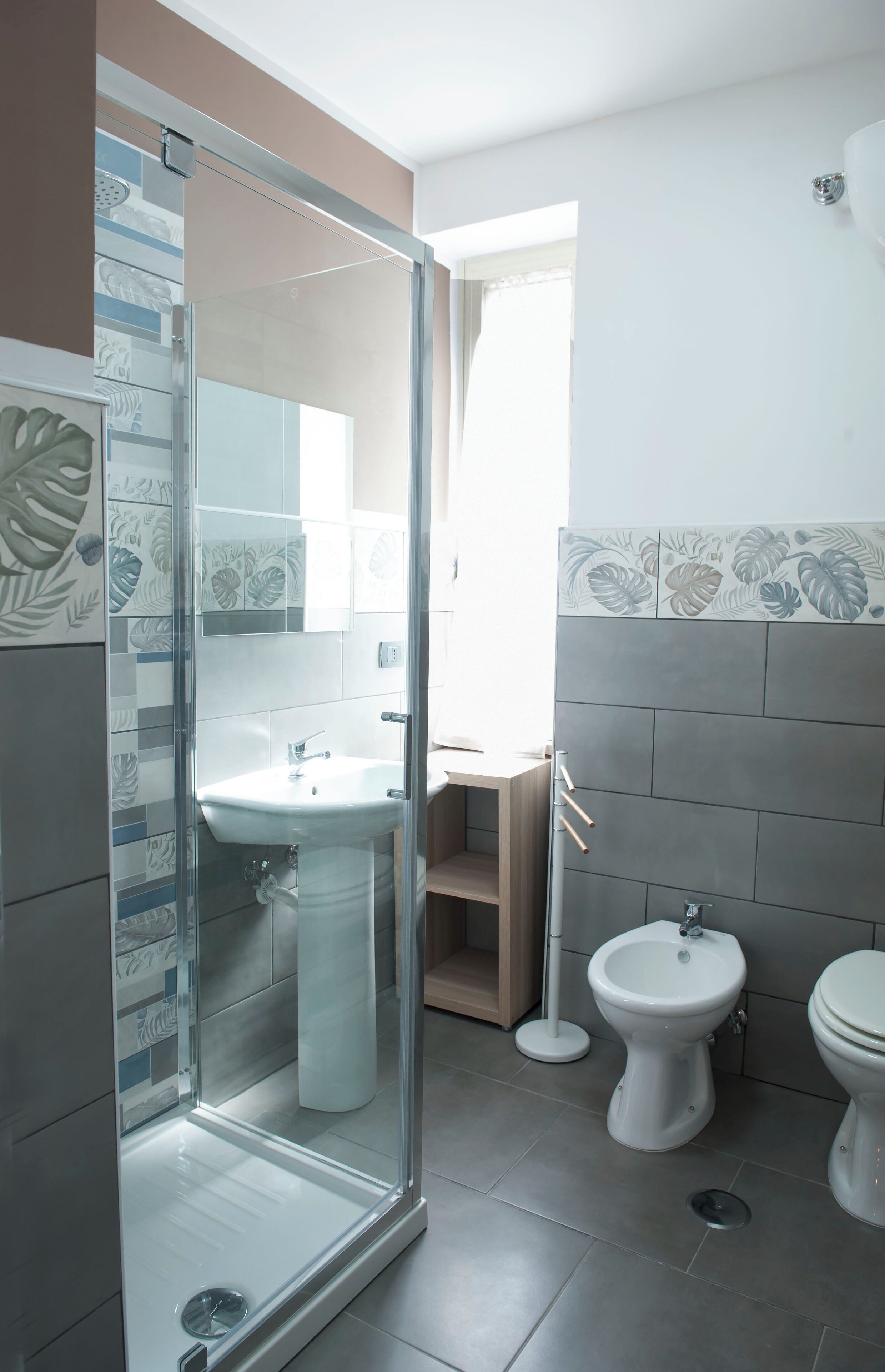 Un bany modern amb una dutxa de vidre, un lavabo amb peu, un vàter i un vàter.
