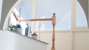 Eine Treppe mit hölzernem Geländer, einem Blumentopf und Blick auf ein Gebäude.