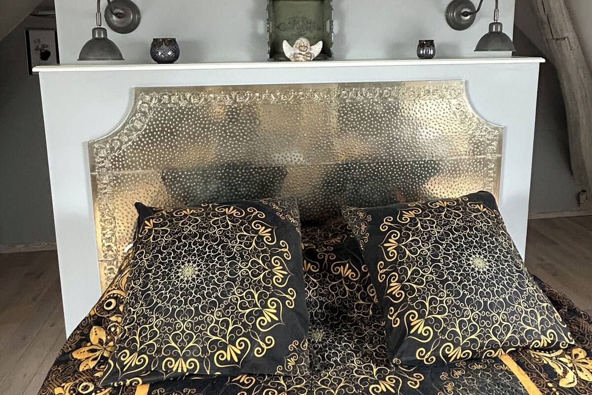 A bedroom with a bed, a white headboard, and two bedside lamps.