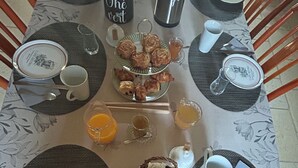 A breakfast table set with plates, cups, a thermos, and a basket of bread. - Chambre d'Hôtes Ecole de Mathuna (Jaunay-Marigny)