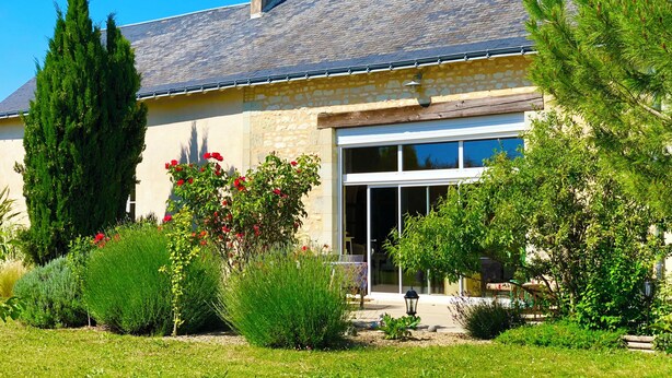 A two-story house with a stone facade, a tiled roof, and a large garage door. - Chambre d'Hôtes Ecole de Mathuna (Jaunay-Marigny)