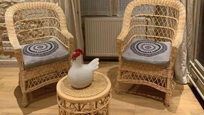 Two wicker armchairs with patterned cushions, a small round table with a decorative vase, and a stone wall. - Chambre d'Hôtes Ecole de Mathuna (Jaunay-Marigny)