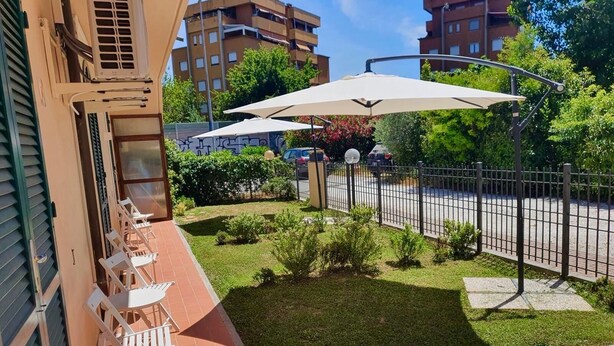 Ein Balkon mit Sitzgelegenheit im Freien, einer kleinen Rasenfläche und einem Zaun.