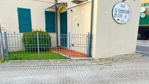 Ein Gebäudeeingang mit einem Metallgitter, einer kleinen Gartenanlage und einem Schild mit der Aufschrift 'B&B IL GIARDINO DI ZIO'.