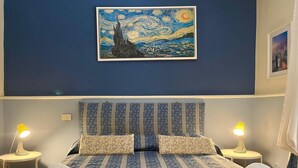 Ein Schlafzimmer mit einem Bett, zwei Nachttischlampen, einem Bild an der Wand und Handtüchern auf dem Bett.