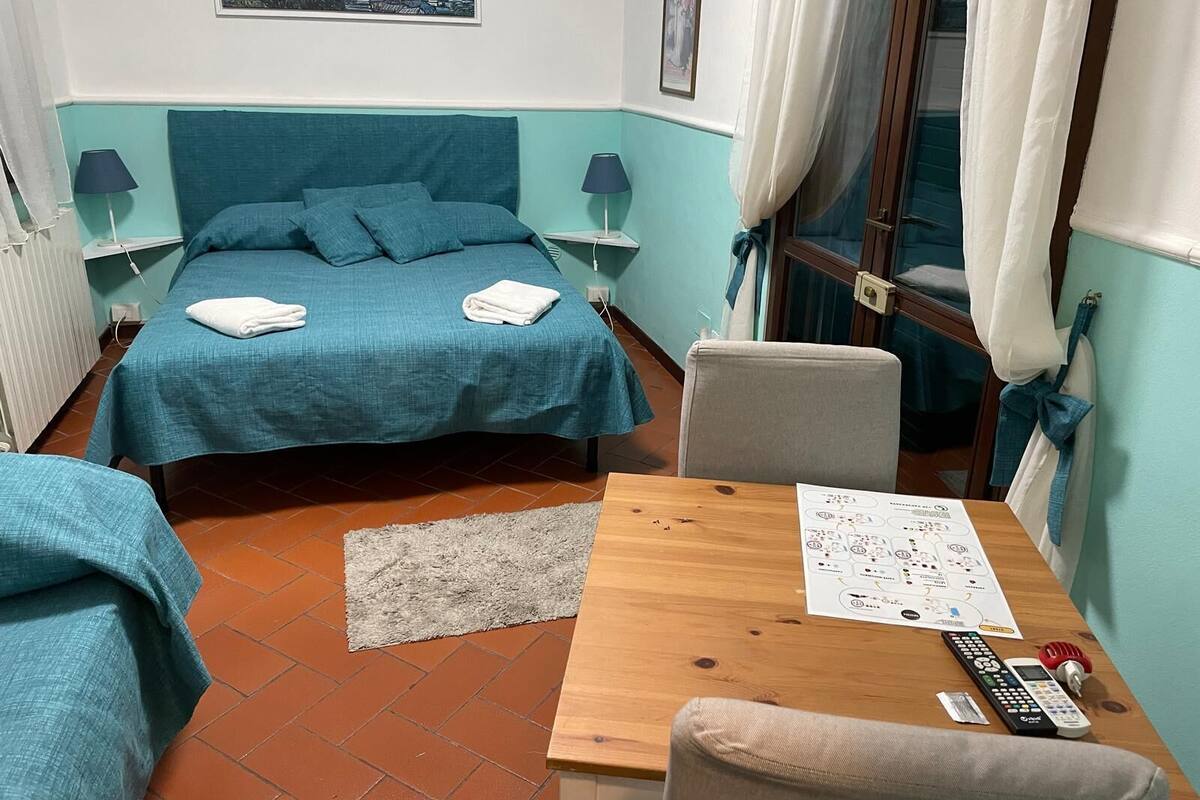 Una camera da letto con un letto, due comodini, una scrivania in legno, una sedia e una finestra con tende.