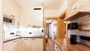 A modern kitchen with white cabinetry, a stone backsplash, and wooden countertops. - Käserstube Ferienwohnungen (Tannheim)