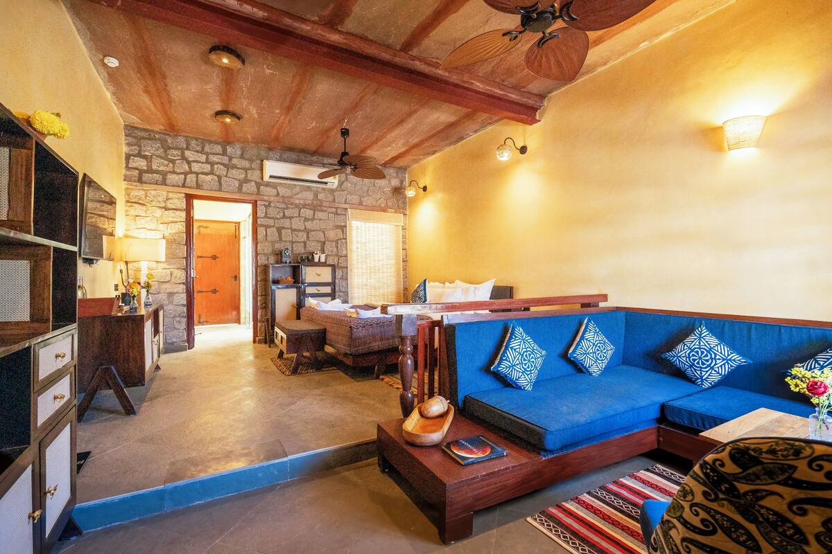Un salon chaleureux avec un canapé bleu, une table basse en bois et un mur en pierre.
