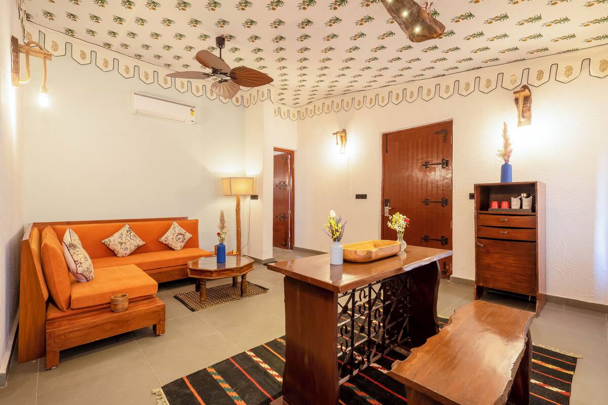 Un salon comprenant un canapé, une table basse et une table d’appoint en bois. On y trouve également un ventilateur de plafond, un climatiseur mural et un meuble en bois doté de tiroirs.