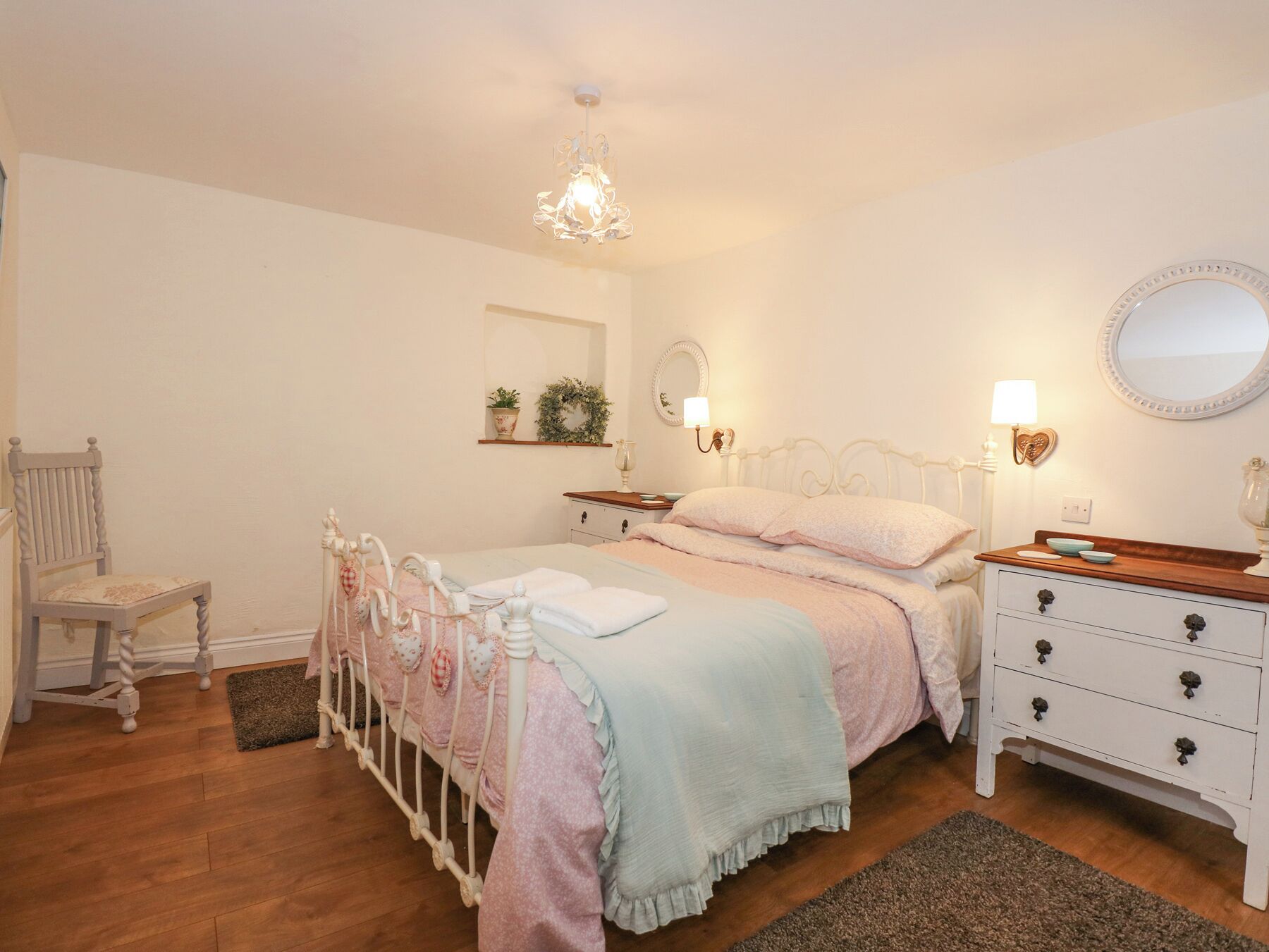 A bedroom with a bed, bedside tables, a chair, and a dresser.