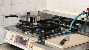 Cozinha com fogão a gás, frigideira, panela, tábua de corte e faca.