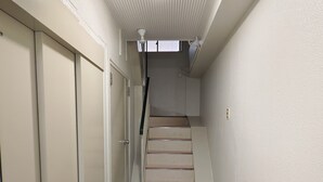 Um corredor estreito com escada que dá para um patamar.