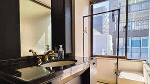 Casa de banho moderna com toucador preto, um espelho grande e janela com vista para edifícios.