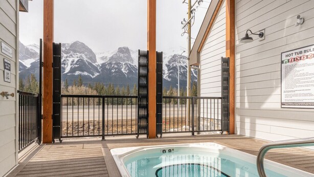 A hot tub area with a mountain view, wooden deck, and a sign about hot tub rules. - Sky Ridge Heights| Outdoor Hot Tub | Parking (Harvie Heights)