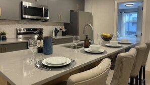 A modern kitchen with grey cabinets, stainless steel appliances, and a central island with seating. - Sky Ridge Heights| Outdoor Hot Tub | Parking (Harvie Heights)