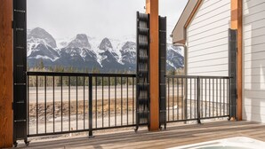 A wooden deck with a hot tub, a metal fence, and a view of snow-capped mountains. - Sky Ridge Heights| Outdoor Hot Tub | Parking (Harvie Heights)