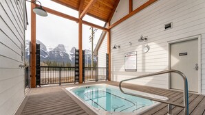 A hot tub area with a view of snow-capped mountains, wooden deck, and a sign indicating hot tub rules. - Sky Ridge Heights| Outdoor Hot Tub | Parking (Harvie Heights)